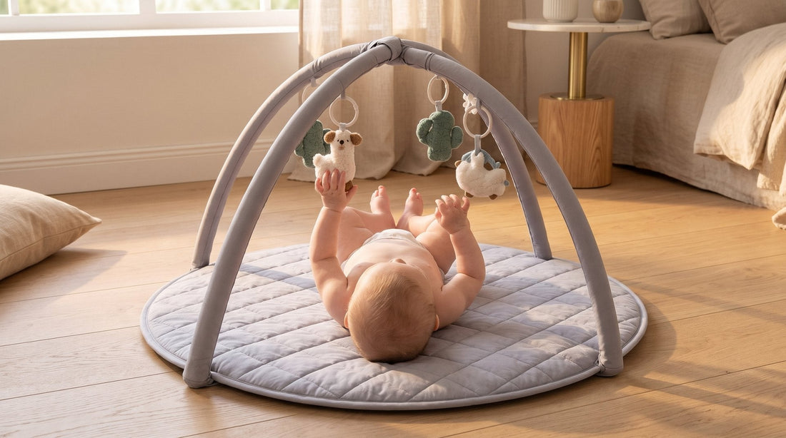Baby van 3 maanden op de ronde grijze babygym van Laavir, reikend naar een hangspeeltje