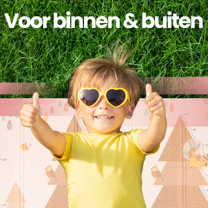 Opvouwbare baby speelmat met dierenprint en tas - kind speelt buiten in gras.